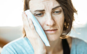A Caucasian woman holding her right cheek due to tooth pain