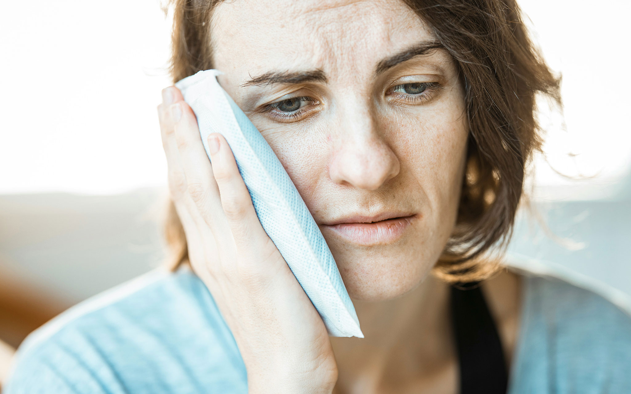 A Caucasian woman holding her right cheek due to tooth pain