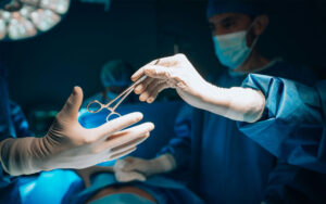 A surgeon handing a scissor to another surgeon in an operating room.